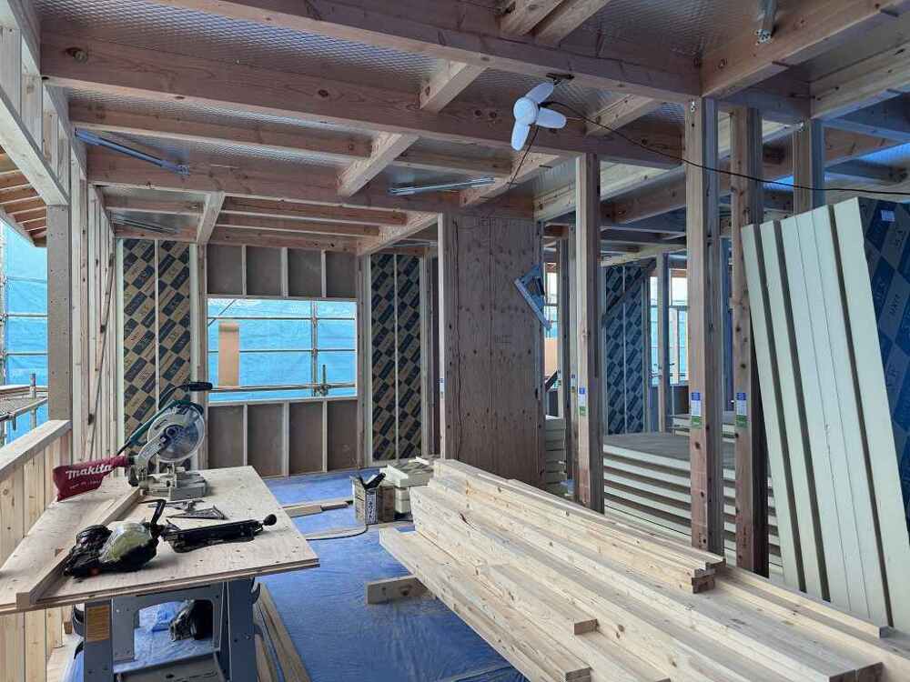 SWパネル施工工事の画像／木造住宅の建物内部で、大工が重量のあるスーパーウォールパネルを運び、柱や梁の間に取り付ける作業を進めている様子