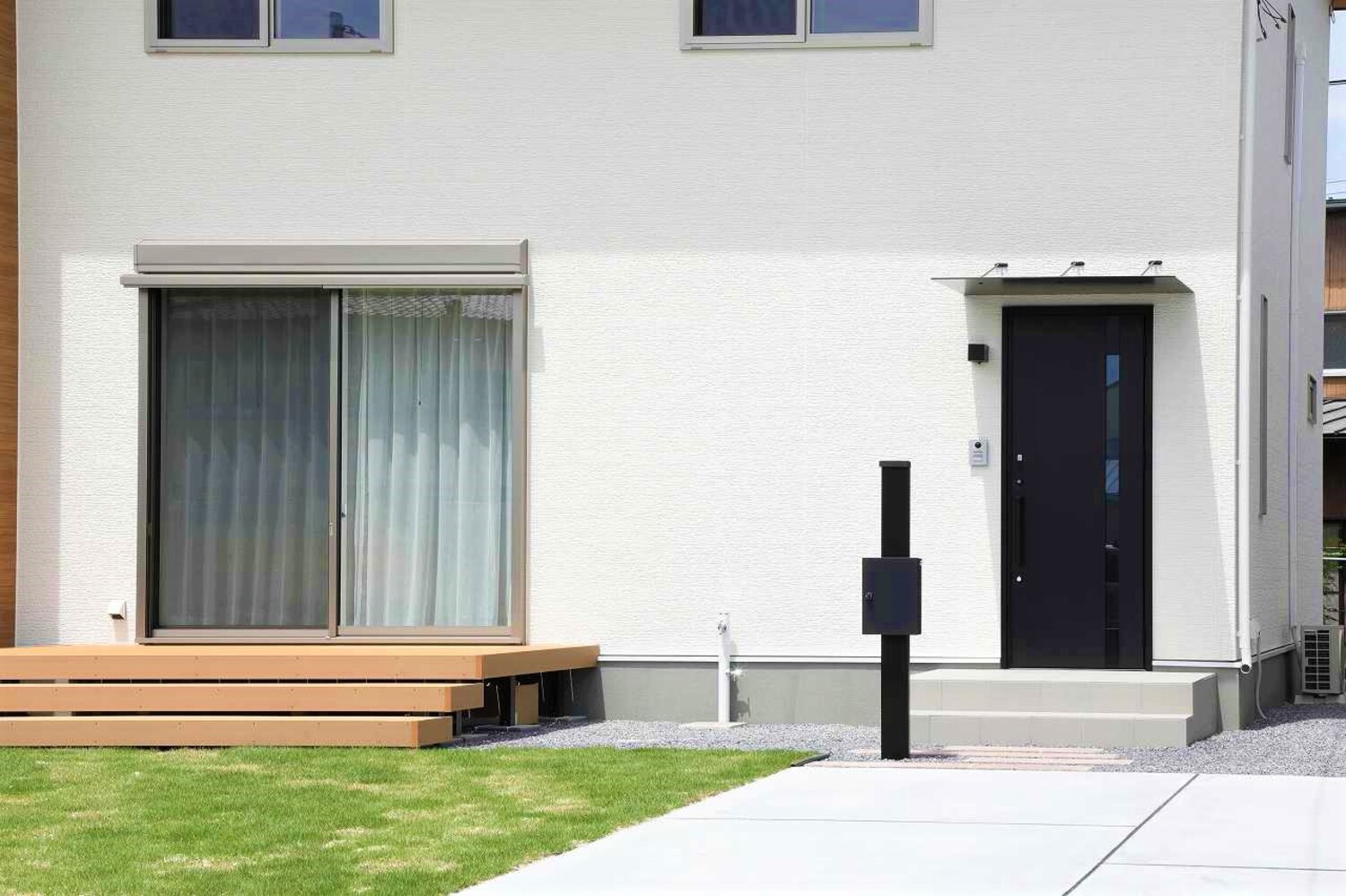 住宅のアプローチ写真(芝生、デッキ、黒いポスト)