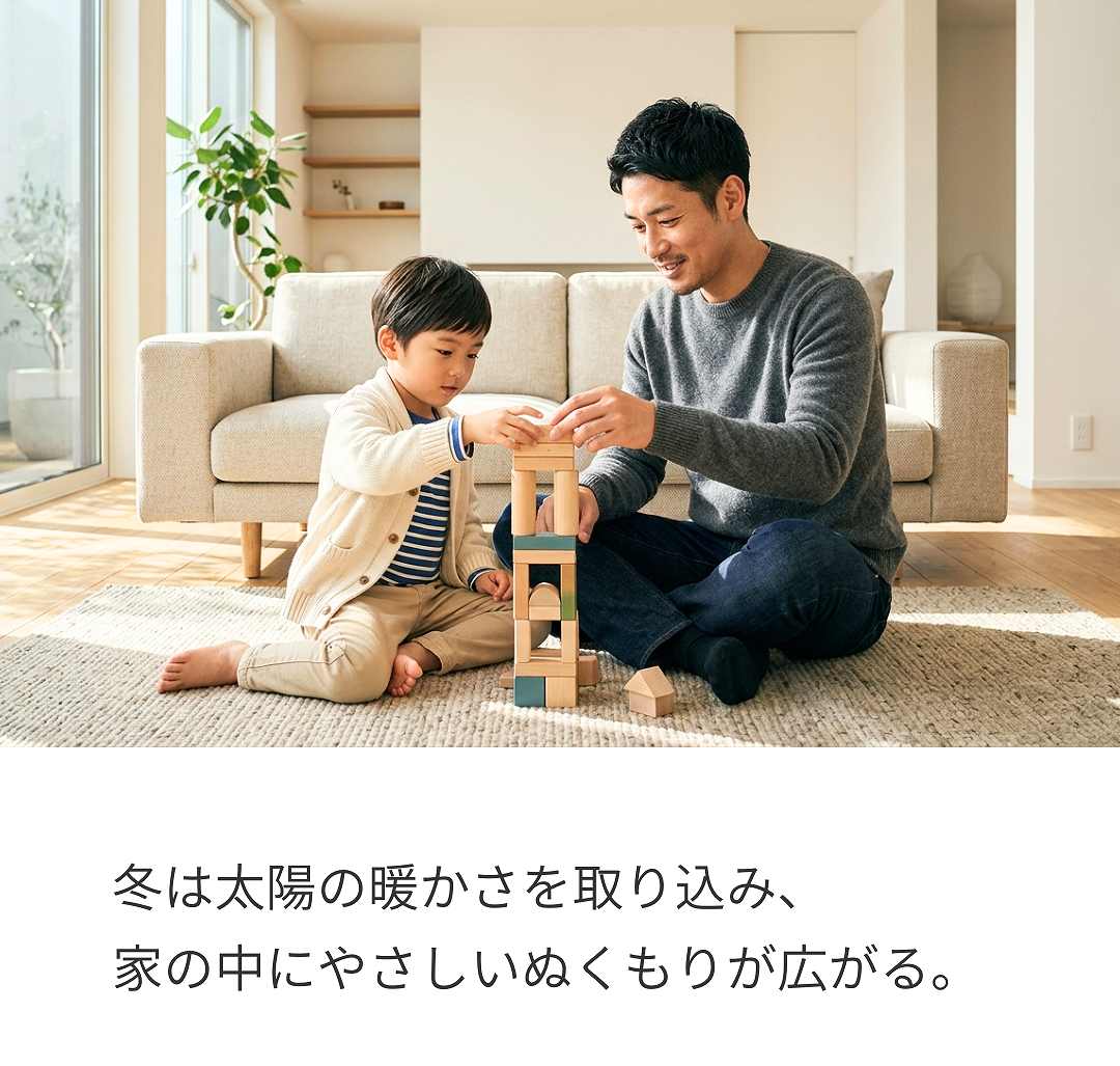 冬、太陽の日差しが入る暖かなリビングで遊んでいる親子のイメージ画像